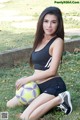 A woman sitting on the grass with a soccer ball.