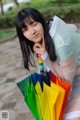 A woman holding a bunch of colorful umbrellas in her hands.