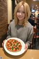 A woman holding a plate with a pizza on it.