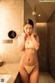 A woman in a white lingerie standing in a bathroom.
