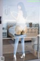 A woman in a white bodysuit and jeans standing in front of a glass door.