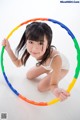 A young girl is playing with a hula hoop.