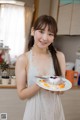 A woman holding a plate with a cake on it.