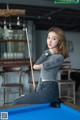 A woman sitting on top of a pool table holding a cue.