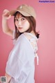 A woman wearing a white shirt and a brown hat.