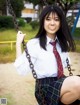 A woman in a school uniform sitting on a swing.