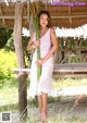 A woman in a pink dress holding a bunch of grass.