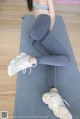 a woman sitting on a yoga mat wearing a gray sports bra top and grey leggings