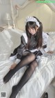 a woman sitting on top of a bed in a maid outfit