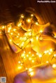 A naked woman laying on a wooden floor covered in lights.