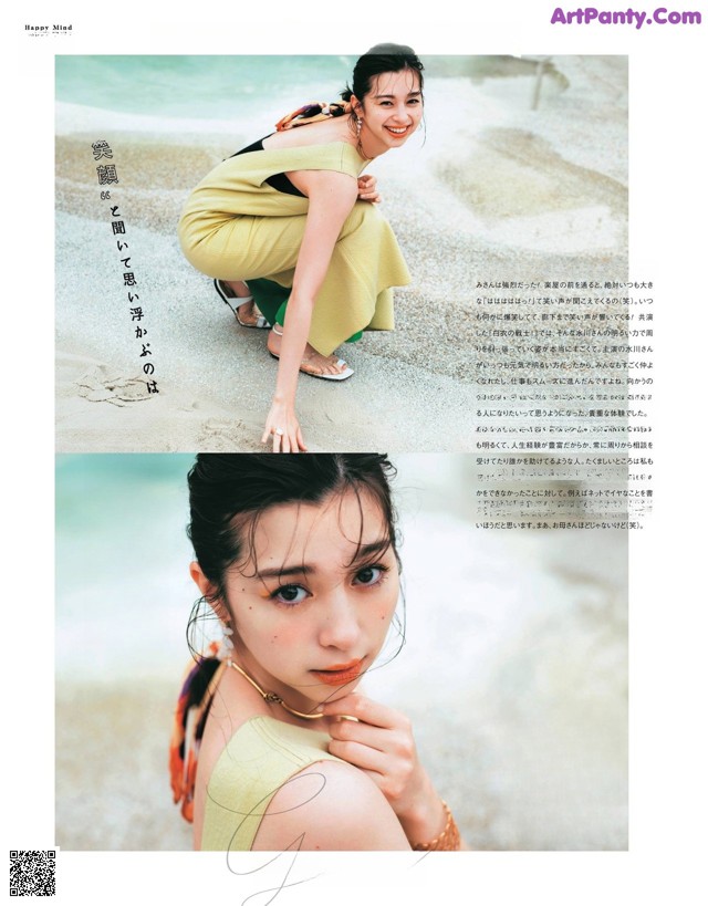 A woman in a yellow dress crouching down on the beach.