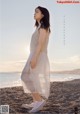 A woman standing on a beach next to the ocean.