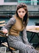 A woman sitting on a wooden bench next to a table.