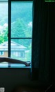 A person laying on a window sill in front of a window.