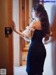 A woman in a black dress standing in front of a door.