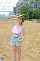 A woman standing on top of a sandy beach next to a volleyball net.