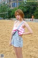 A woman standing on top of a sandy beach next to a volleyball net.