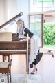 A woman in a maid outfit sitting at a piano.