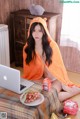 A woman sitting on a bed with a laptop and a plate of fruit.