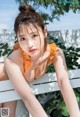 A woman in an orange bathing suit sitting on a white bench.