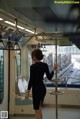 A woman in a black dress standing on a subway train.