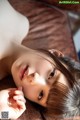 A woman laying on top of a brown couch.