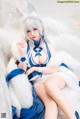 A woman in a blue and white outfit sitting on a white couch.