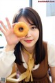 A woman holding a donut in front of her face.