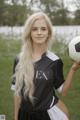 A young woman holding a soccer ball in a field.