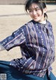 A woman sitting on the ground wearing a blue skirt and a blue shirt.