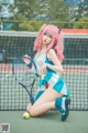 A woman with pink hair holding a tennis racket on a tennis court.